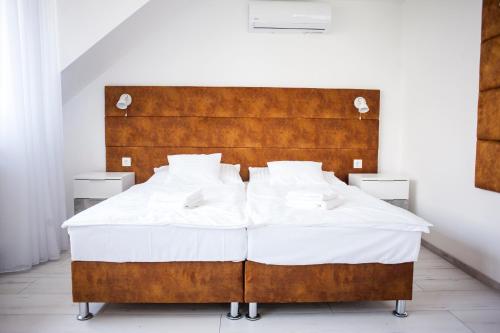 a large bed with white sheets and a wooden headboard at Q-Panzió in Tata