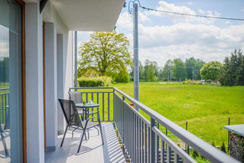 a balcony with a table and chairs and a field at APARTAMENTY PIAMOLA Willa Zacisze Kąty Rybackie in Kąty Rybackie