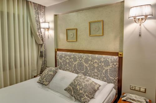 a bedroom with a bed with a headboard and two lamps at Bulbul Yuvası Boutique Hotel in Foca
