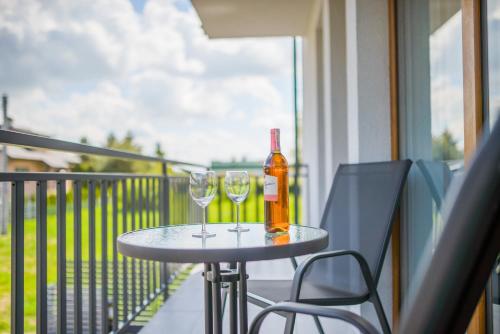 a table with two glasses and a bottle of wine on a balcony at APARTAMENTY PIAMOLA Willa Zacisze Kąty Rybackie in Kąty Rybackie