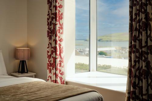 a bedroom with a window with a view of the ocean at Dingle Harbour Lodge B&B in Dingle