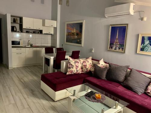 a living room with a purple couch and a kitchen at Apartments MM in Sveti Stefan