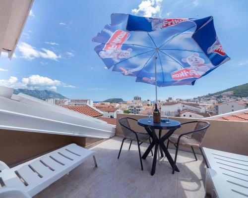 - un balcon avec une table, des chaises et un parasol dans l'établissement Apartments Pedja Zec, à Budva