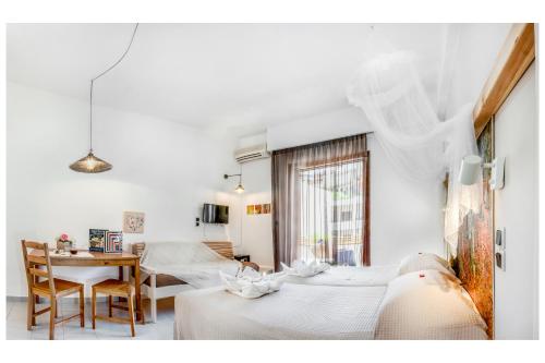 een kamer met witte muren en een tafel en 2 bedden bij Tree of Life Art Hotel in Agia Marina Nea Kydonias