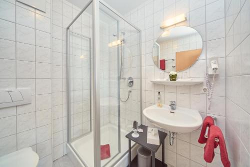 a white bathroom with a shower and a sink at Hotel-Krone-Lounge in Herdwangen-Schönach