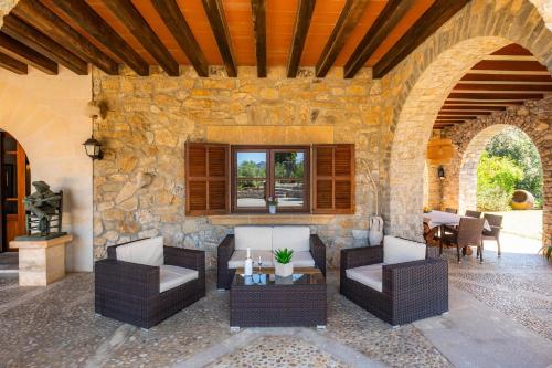 a patio with chairs and tables and a stone wall at Es Voltor in Artá