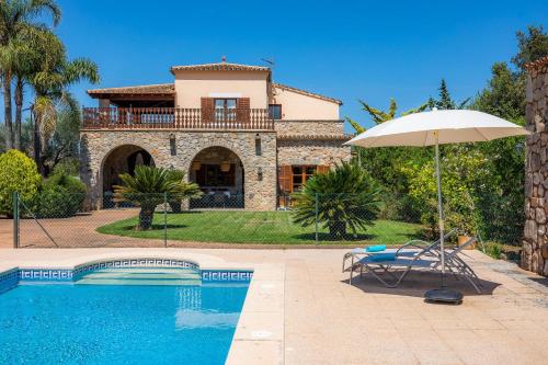 a house with a swimming pool and an umbrella at Es Voltor in Artá