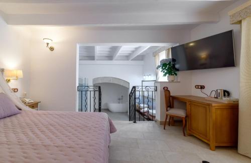 a bedroom with a bed and a desk and a bathroom at Seranova Luxury Hotel - Adults Only in Ciutadella
