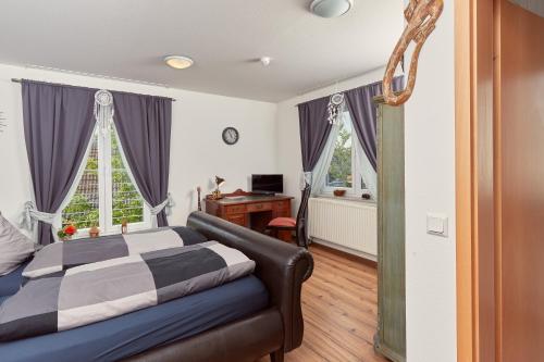 a bedroom with a bed and a desk and two windows at Hotel-Krone-Lounge in Herdwangen-Schönach