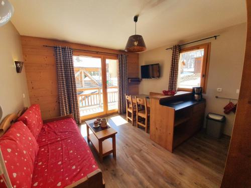 a living room with a red couch and a kitchen at Les Chalets Des Rennes - VARS - T2 4 personnes - CDRA53 in Vars