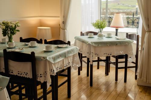 a dining room with two tables and chairs and a window at The Waterfront in Dingle