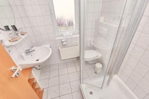 a white bathroom with a sink and a toilet at Hotel-Krone-Lounge in Herdwangen-Schönach