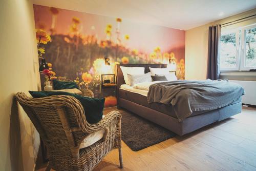 1 dormitorio con cama y silla de mimbre en Boutique Hotel LANDHAUSZEIT en Bad Münstereifel