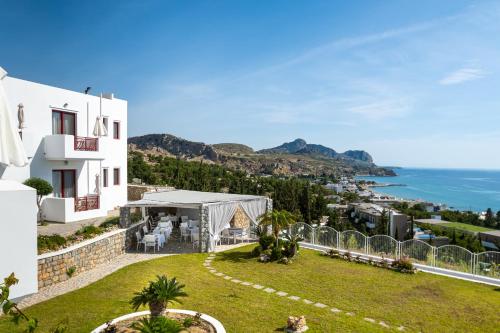 Blick auf ein Haus mit Rasen und Meer in der Unterkunft Bella Vista Stegna in Archangelos