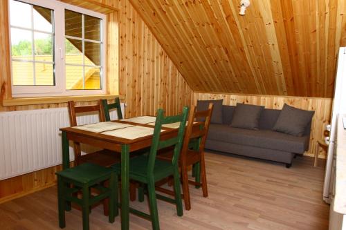 a dining room with a table and chairs and a couch at Asvejos slenis in Sužionys