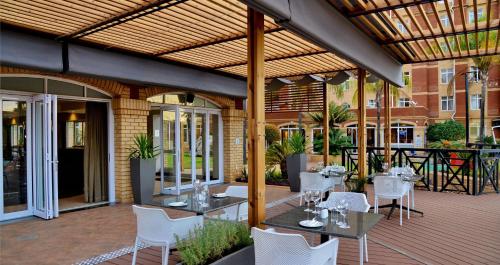 a patio area with tables, chairs and umbrellas at ANEW Hotel Centurion Pretoria in Centurion