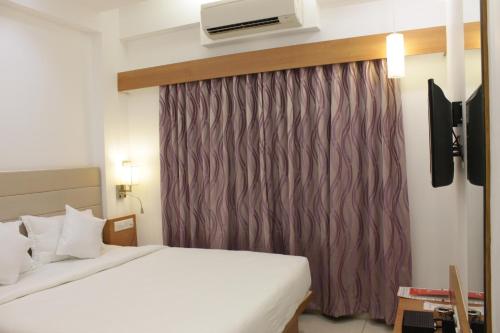 a hotel room with a bed and a window with a air conditioner at Hotel Ashray Inn in Ahmedabad