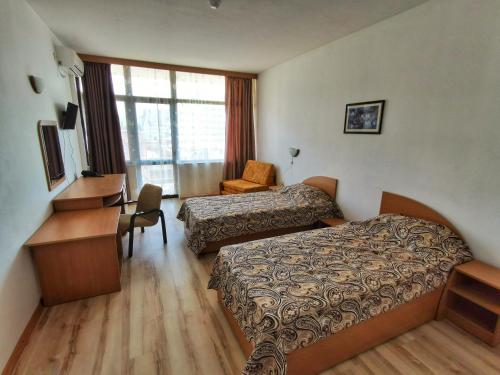 a hotel room with two beds and a desk at Hotel Trakia Garden in Sunny Beach