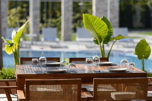 a wooden table with plates and wine glasses on it at Miamar Luxury Hotel & Spa in Himare