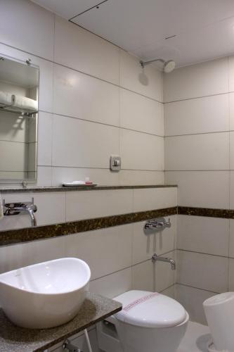 a bathroom with a sink and a toilet and a mirror at Hotel Ashray Inn in Ahmedabad