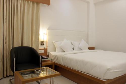 a hotel room with a bed and a chair at Hotel Ashray Inn in Ahmedabad
