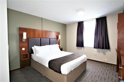 a hotel room with a large bed and a large window at The Oakwood Hotel by Roomsbooked in Gloucester
