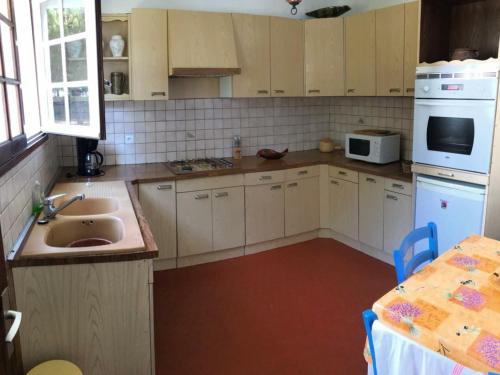 - une cuisine avec des placards blancs, un évier et une table dans l'établissement Maison typique avec grand jardin, proche plage, 3 chambres à St-Hilaire-de-Riez - FR-1-426-279, à Saint-Hilaire-de-Riez