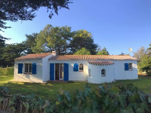 Une petite maison blanche avec volets bleus dans l'établissement Maison typique avec grand jardin, proche plage, 3 chambres à St-Hilaire-de-Riez - FR-1-426-279, à Saint-Hilaire-de-Riez