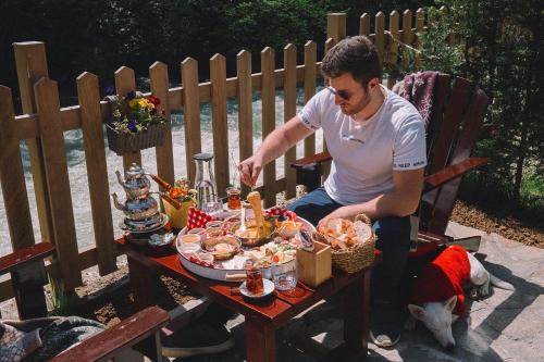 a man sitting at a table with food on it at DREAM RIVER EXCLUSIVE BUNGALOW in Çamlıhemşin