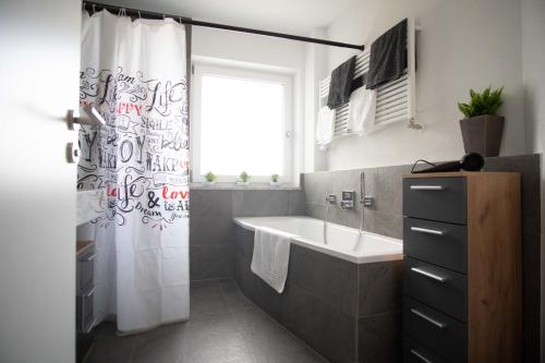 a bathroom with a sink and a shower curtain at Ferienwohnung FühlDichWohl in Übersee