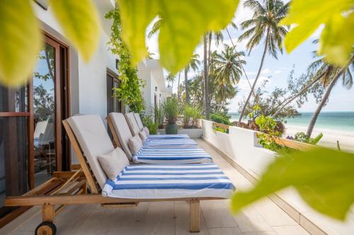 a row of chaise lounge chairs on a balcony overlooking the beach at Surfescape Zanzibar in Kiwengwa