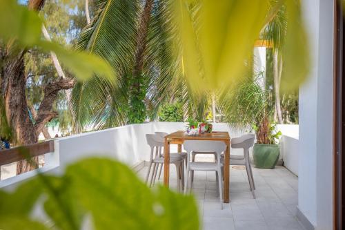 a table and chairs on a patio with palm trees at Surfescape Zanzibar in Kiwengwa
