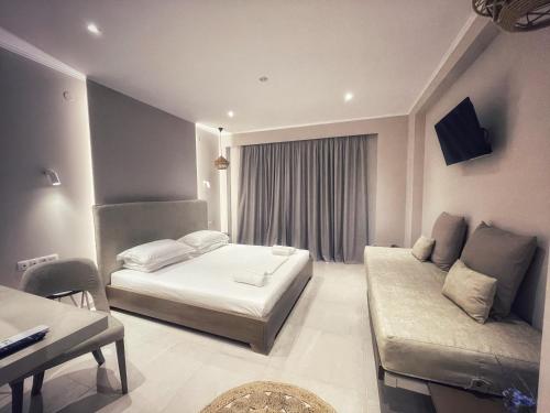 a hotel room with two beds and a couch at Scarabeo Suites & Villas Parga in Parga