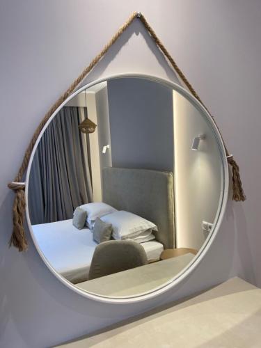a mirror on a wall with a bed and a chair at Scarabeo Suites & Villas Parga in Parga