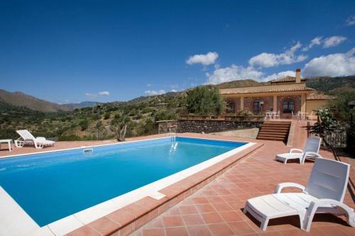 una piscina con 2 sillas y una casa en Il Poggio Country Resort, en Graniti