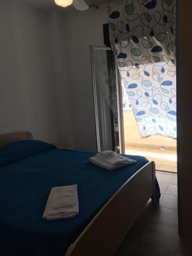 una camera da letto con un letto con lenzuola blu e una finestra di Appartamento di Lampedusa a Lampedusa