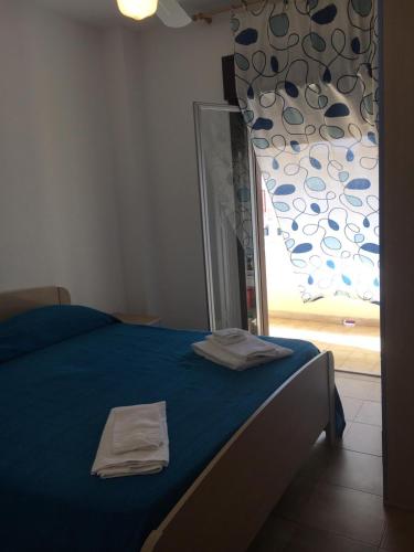 una camera da letto con un letto con lenzuola blu e una finestra di Appartamento di Lampedusa a Lampedusa