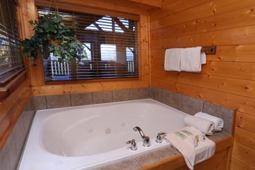 a large white tub in a wooden bathroom with a window at His Amazing Grace in Sevierville