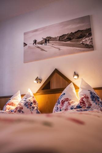 a bedroom with a bed with pillows and a picture on the wall at Appartements Romantika & Appartement Barbara in Wagrain