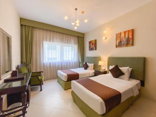 um quarto de hotel com duas camas e uma secretária em Auris Boutique Hotel Apartments - AlBarsha em Dubai