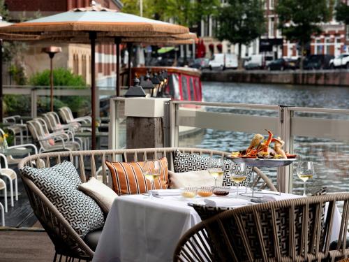 a table with chairs and a table with food on it at De L’Europe Amsterdam – The Leading Hotels of the World in Amsterdam