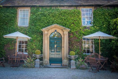 a house with a green door and tables and umbrellas at Rafters at Riverside House Hotel in Bakewell