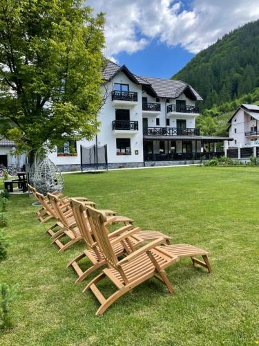 four chairs sitting in the grass in front of a building at Pensiunea Edelweiss in Voineasa