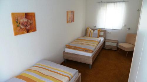 ヴィリンゲンにあるFerienwohnungen Mittendrinのベッド3台、椅子、窓が備わる客室です。