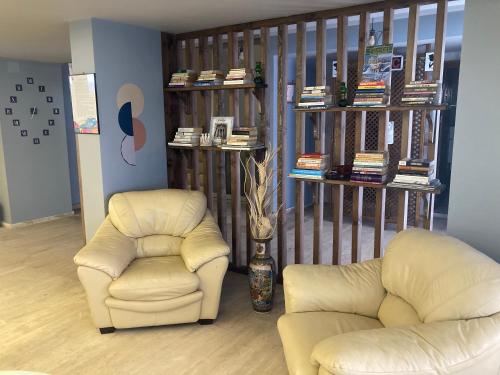 a living room with two chairs and a book shelf at Olimpia Hotel in Fethiye