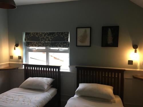two beds in a bedroom with a window and two pillows at Twin Oaks Guest House in Cadnam
