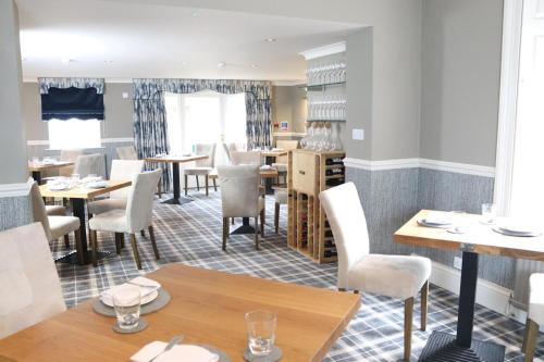 uma sala de jantar com mesas e cadeiras brancas em Rafters at Riverside House Hotel em Bakewell