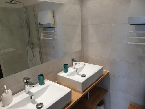 une salle de bain avec deux lavabos blancs et un miroir dans l'établissement Brigantine Marines de Cogolin, à Cogolin