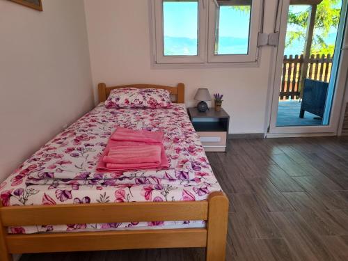 Schlafzimmer mit einem Bett mit rosa Bettwäsche und einem Fenster in der Unterkunft Apartmani Kuljanin in Donji Milanovac