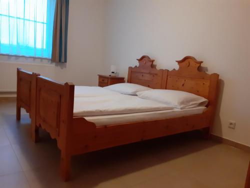 a bedroom with a wooden bed with white sheets at Pension Horvath jun. in Guntramsdorf